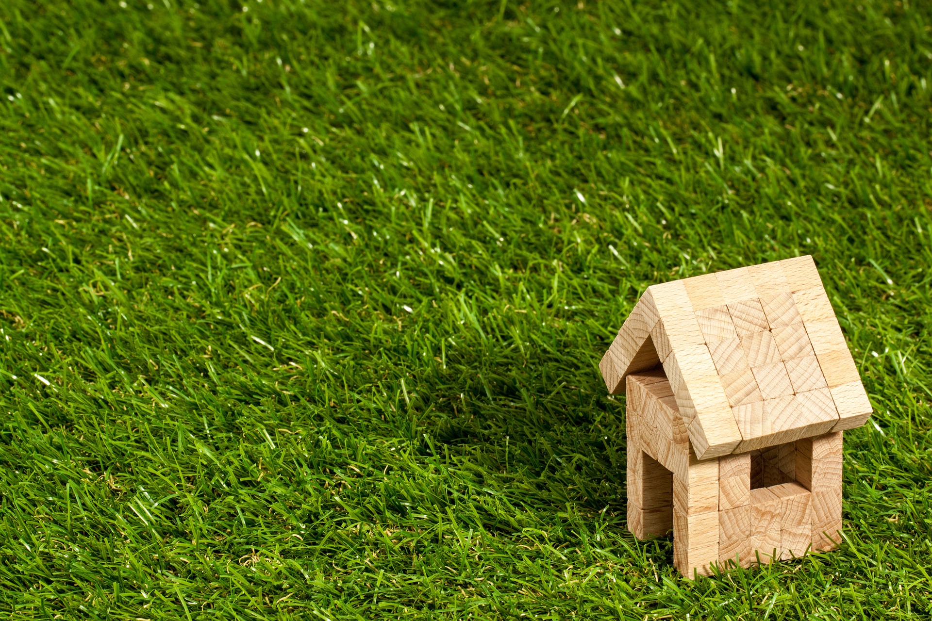 Miniature, wooden block home sitting on grassed ground