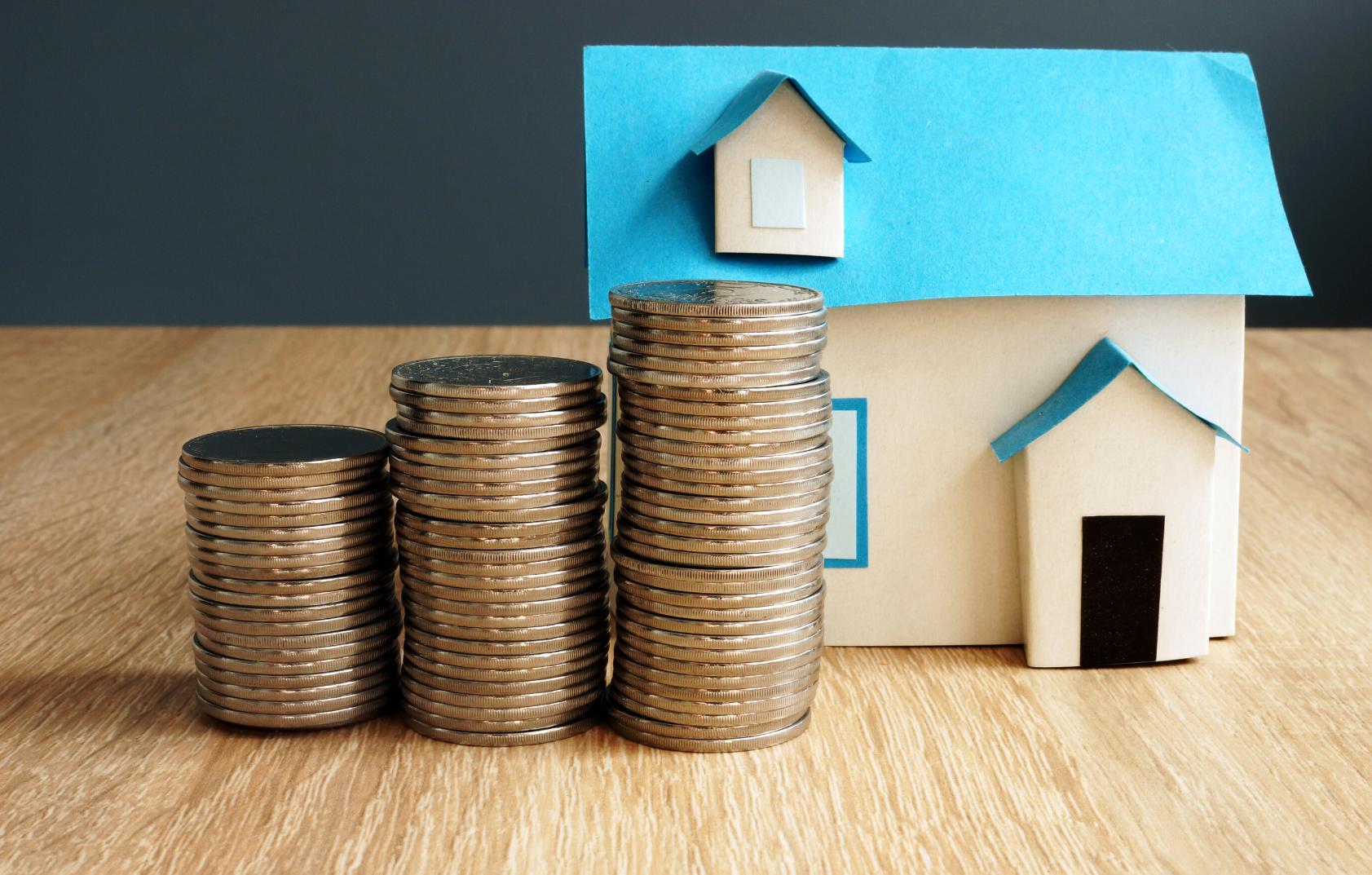 Residential property made out of paper with three stacks of coins to the side