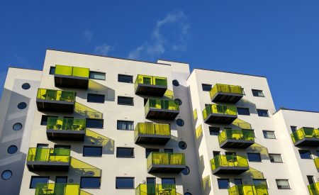 Block of flats in England with green glass balconies set against a blue sky