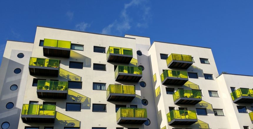 Block of flats in England with green glass balconies set against a blue sky