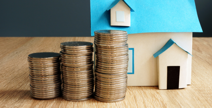 Residential property made out of paper with three stacks of coins to the side