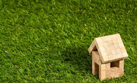 Miniature, wooden block home sitting on grassed ground