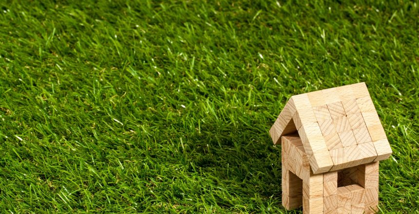 Miniature, wooden block home sitting on grassed ground